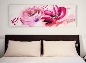 a painting of pink flowers above a bed at il 64B - 10 minuti a piedi dal Policlinico San Matteo - in Pavia +38 photos