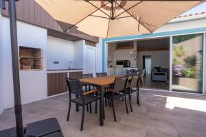 a kitchen and dining room with a table and chairs and an umbrella at São Jorge Holiday Homes in Velas