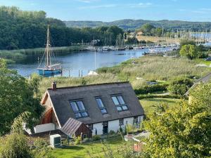 a house on a hill next to a river with a boat at Seedorf Hideaway, Reethaus mit Garten und Privatsteg, Kamin, Sauna und Hot Tub in Ostseebad Sellin
