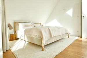 a bedroom with a white bed with a white rug at Seedorf Hideaway, Reethaus mit Garten und Privatsteg, Kamin, Sauna und Hot Tub in Ostseebad Sellin