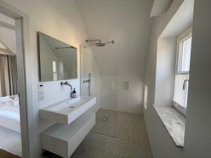 a white bathroom with a sink and a mirror at Seedorf Hideaway, Reethaus mit Garten und Privatsteg, Kamin, Sauna und Hot Tub in Ostseebad Sellin +14 photos