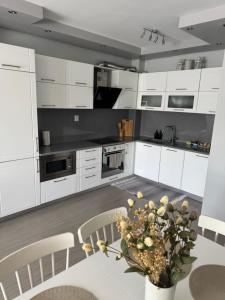 a kitchen with white cabinets and a table with a vase of flowers at Guest Apart Arda in Kŭrdzhali