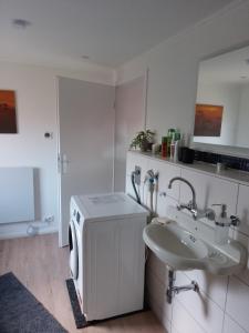 a white bathroom with a sink and a washing machine at Heimathafen Hamelwörden in Wischhafen