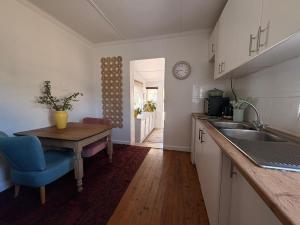 a kitchen with a table and a sink and a counter at Cosy Coastal Hideaway in Hermanus