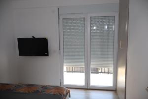 a room with two sliding glass doors and a television at Apartman SASHA in Bar