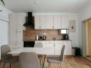 a kitchen with white cabinets and a table and chairs at Apartman Silvia in Breitenau