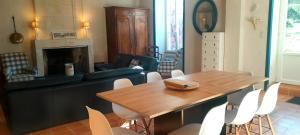 a living room with a wooden table and white chairs at Logis de Chenac - Chambres et table d'hôtes in Chenac Saint Seurin D'uzet