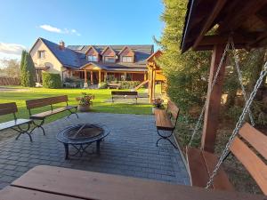 a patio with benches and a fire pit in front of a house at Agroturystyka u Jarka in Bryzgiel