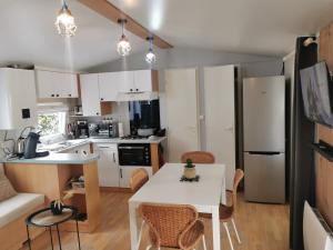 a small kitchen with a white table and chairs at Mobil-home cosy avec terrasse et jardin privatif in La Bernerie-en-Retz