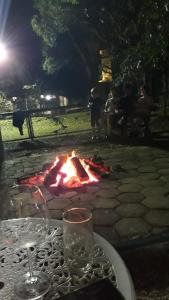 a table with a wine glass and a fire pit at Ecos Jatobá - Refúgio à 12 km do Santuário de Aparecida in Guaratinguetá