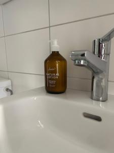 a bottle of liquid soap sitting on a bathroom sink at La Garçonnière in Colombier