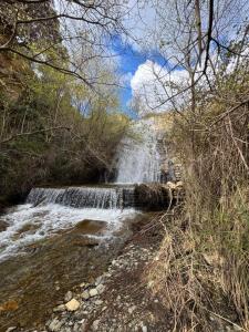 a waterfall in the middle of a river with trees at Arroyo Alpujarra in Guarros
