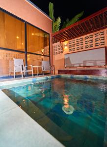 a swimming pool with chairs and a house at Résidence Akia - Jacuzzi privé & détente moderne in Pointe-Noire