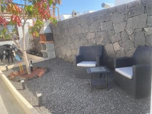 two chairs and a table in front of a stone wall at Apartamento Casa Leo in Playa Blanca