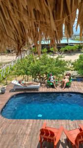 two people sitting in lawn chairs next to a swimming pool at Playa Escondida Mayapo in Mayapo