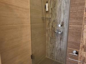 a shower stall with a glass door with a shower at Captain's Tolo Sea View 2 in Tolo
