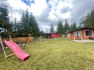 a playground with a slide and a house at Zacisze 6 osobowy Domek nad jeziorem in Świętne