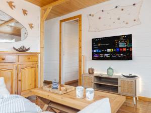 a living room with a tv and a table at L'authentique chalet en bois sur pilotis in Gruissan