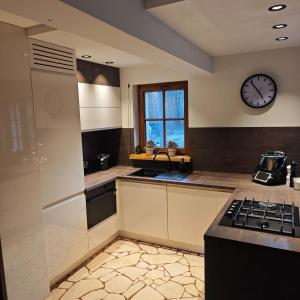 a kitchen with a sink and a clock on the wall at Leśny Relaks in Krasiejów