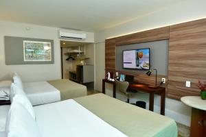 a hotel room with two beds and a desk at Hotel Atlante Plaza in Recife