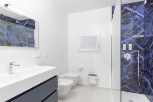 a white bathroom with a sink and a toilet at Domo Cicindela Boutique Rooms Centro Carloforte in Carloforte +8 photos
