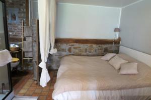 a bed in a bedroom with a brick wall at La maison de Barbara in Aubel