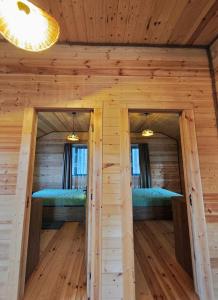two beds in a log cabin with two windows at Pinewood Surami in Surami