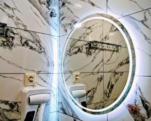 a bathroom with a round mirror on a wall at Pinewood Surami in Surami