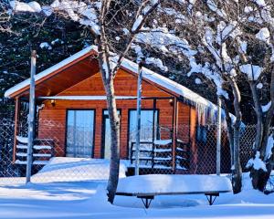 a log cabin with a bench in the snow at Pinewood Surami in Surami
