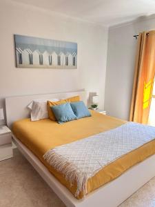 a bedroom with a large bed with yellow and blue pillows at Casa da Charrua in São Teotónio