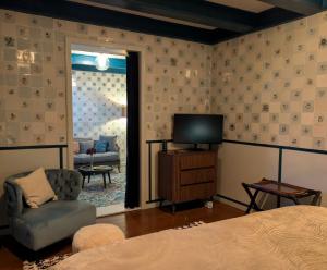 a bedroom with a bed and a tv and a chair at De Tegel Suite in Anjum
