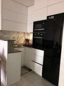 a kitchen with black appliances and white cabinets at apartment in Itʼkhvisi