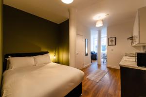 a bedroom with a white bed and a kitchen at 8 Stanley Street Apart-Hotel in Liverpool