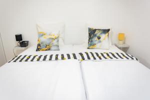 a white bed with two pillows on top of it at Aimeelie - spacieux T3 avec piscine, terrasse, idéal famille, calme et lumineux in Lamentin