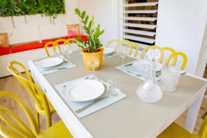 a white table with plates and glasses on it at Aimeelie - spacieux T3 avec piscine, terrasse, idéal famille, calme et lumineux in Lamentin +26 photos