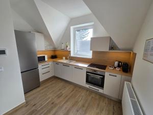 a kitchen with white cabinets and a window at Harmónia Apartmanház in Kőszeg