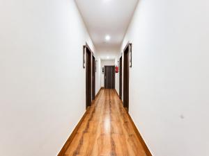 a hallway with a wooden floor and white walls at Townhouse Royal Inn in Guwahati