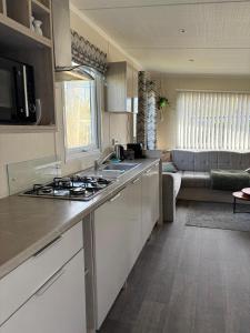a kitchen with a stove top oven next to a living room at Vakantiehuisje op 5 star kindercamping in Mariënberg