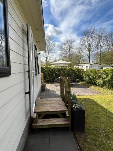 a porch with a wooden bench on the side of a house at Vakantiehuisje op 5 star kindercamping in Mariënberg