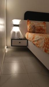 a bedroom with a bed and a nightstand with a light at GALSEN LODGe in Thiès