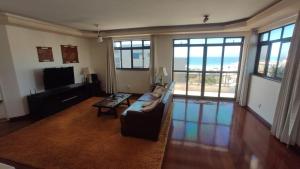 a living room with a couch and a tv and windows at Varanda do forte in Cabo Frio
