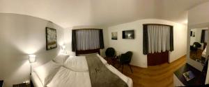 a bedroom with a bed and two chairs and two windows at Gasthof Tenne - Ferie mit Härz in Lenk