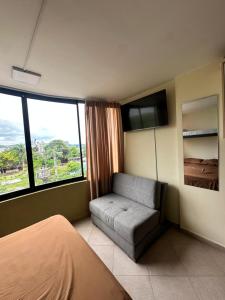 a bedroom with a bed and a couch and a tv at Cozy suite and Jacuzzi overlooking the ocean in Volcán Chimborazo