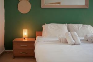 a bed with white pillows and a night stand with a lamp at Porto by Shmoo! in Is-Swieqi