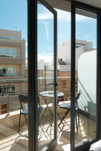 a balcony with glass doors and a table and chairs at Porto by Shmoo! in Is-Swieqi