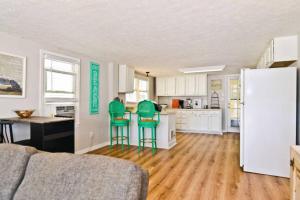 a kitchen with green chairs and a white refrigerator at Modernes Chalet Tanabor mit Bergblick in Lech am Arlberg