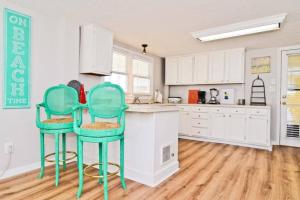 a kitchen with white cabinets and two green bar stools at Modernes Chalet Tanabor mit Bergblick in Lech am Arlberg