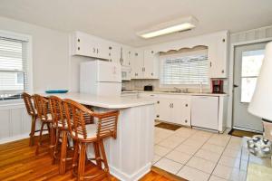 a kitchen with white cabinets and a counter with chairs at Modernes Chalet Tanabor mit Bergblick in Lech am Arlberg +18 photos