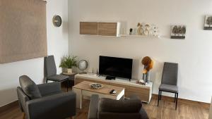 a living room with a flat screen tv and chairs at Apartamentos El PELIGRO 2 LAHIVE in Archidona