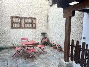 a patio with a red table and chairs next to a building at La Mirada de Juana in Tordesillas
